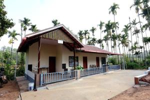 a small building with palm trees in the background at Areca Nut Homestay in Mudigere
