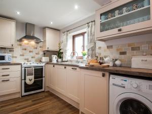 a kitchen with white cabinets and a washer and dryer at Silver Birch Lodge in Horsley +9 photos