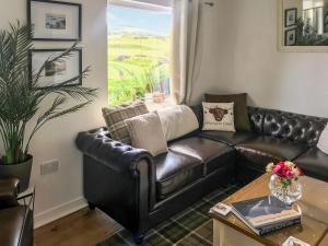 a leather couch in a living room with a table at Harperfield Chalet in Lanark