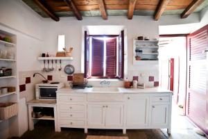 een witte keuken met een wastafel en een raam bij Liotrivi, traditional house in Apollonia