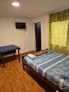 een slaapkamer met een bed, een tafel en een televisie bij Charlotte House in Huanchaco