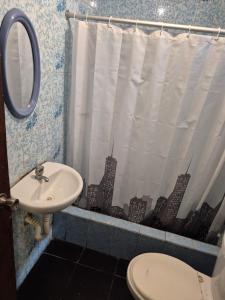 een badkamer met een wastafel, een toilet en een spiegel bij Charlotte House in Huanchaco