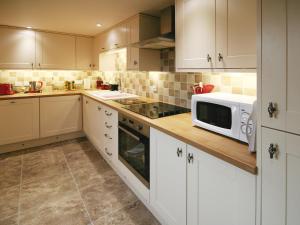 een keuken met witte kasten en een magnetron op een aanrecht bij Granary Cottage - E5626 in Wainfleet All Saints