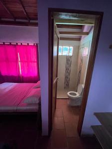 a bedroom with a pink bed and a toilet at Suelo Vivo Eco Hotel in Bochalema