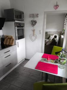 a small kitchen with a white table and a living room at Ferienwohnung Luka in Kaulsdorf +1 photo