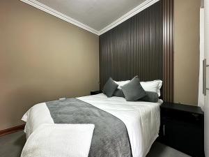 a bedroom with a large bed with white sheets and gray pillows at Zengu in Lusaka +22 photos