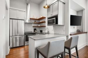 a kitchen with white cabinets and a counter with chairs at King Street Condo - Endless Outdoor Space in Charleston