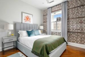 a bedroom with a bed and a brick wall at King Street Condo - Endless Outdoor Space in Charleston