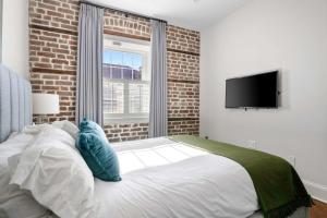 a bedroom with a bed and a tv on a wall at King Street Condo - Endless Outdoor Space in Charleston