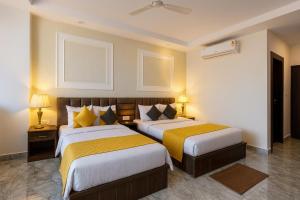 a hotel room with two beds and two lamps at Hotel The Meridian, Haridwar in Haridwār