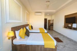 a bedroom with two beds with yellow and white pillows at Hotel The Meridian, Haridwar in Haridwār