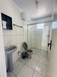 een badkamer met een douche, een toilet en een wastafel bij Pousada Emanuel in Araranguá