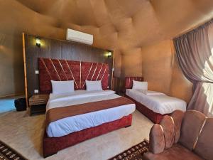 een slaapkamer met 2 bedden en een bank bij Wadi Rum Luxury Camp in Wadi Rum