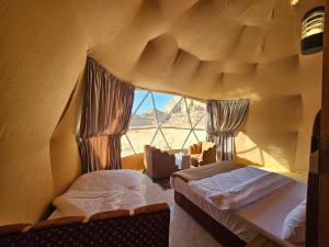 een kamer met twee bedden en een raam bij Wadi Rum Luxury Camp in Wadi Rum
