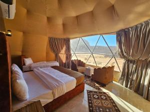een slaapkamer met twee bedden en een groot raam bij Wadi Rum Luxury Camp in Wadi Rum