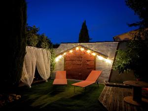 a backyard with two chairs and a tent with lights at Les Elles du Moulin Avec Piscine in Vedène