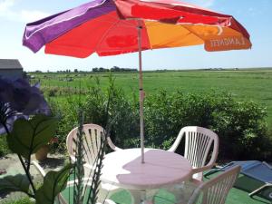a table with a colorful umbrella and chairs at Apartment Nice Holidays by Interhome in Pellworm