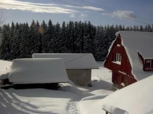 a red barn covered in snow with trees in the background at Holiday Home Elfi by Interhome in Eisenbach