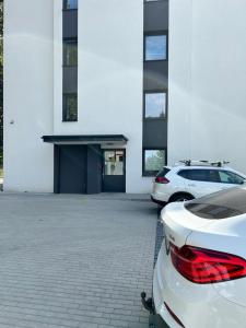 two cars parked in a parking lot in front of a building at Apartament 42 in Sosnowiec