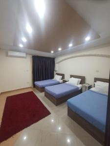 a hotel room with two beds and a red rug at SARAYA AWAD HEGAZI STREET- families only in Alexandria