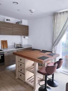 a kitchen with a wooden table and two chairs at Luxury 2-Bedroom London Apartment, 25mins to Liverpool Street, Balcony, Free Parking in London