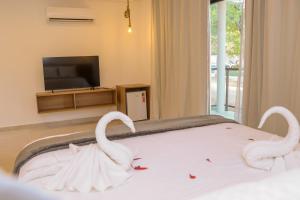 two swans are sitting on a bed in a bedroom at Hotel Maragogi Beach Club in Maragogi