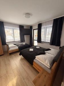 a bedroom with two beds and two windows at Apartament Miś in Zakopane