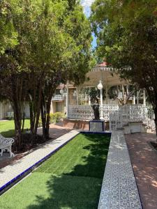 een tuin met witte bankjes en een standbeeld voor een huis bij Hotel Imperial Saltillo in Saltillo +17 foto's