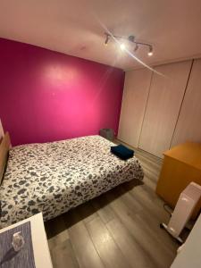 een slaapkamer met een bed en een roze muur bij Le Glatigny in Le Havre