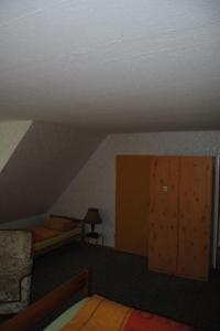 a attic room with a bed and a wooden cabinet at Apartment Schule 6 by Interhome in Goosefeld