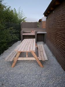 a wooden picnic table sitting next to a brick wall at Freedom in Miramar +2 photos