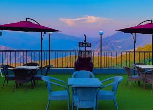 a balcony with tables and chairs with a view of mountains at The Pine Mountain View A Rooftop Restaurant & Luxury Balcony Rooms! in Mussoorie
