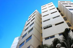 a tall building with a palm tree in front of it at Apart Service Araras - VPC in Caldas Novas