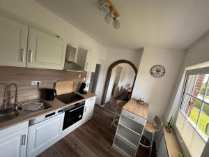 a kitchen with white cabinets and a sink and a window at Huus Christine in Holtgast