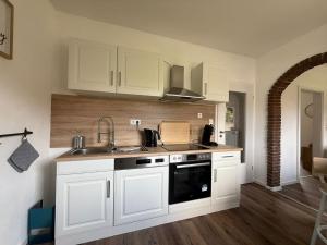 a kitchen with white cabinets and a sink at Huus Christine in Holtgast