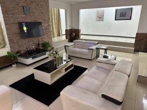 een woonkamer met witte meubels en een flatscreen-tv bij The 12th Avenue in Lusaka