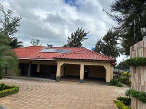 een huis met een rood dak en een oprit van bakstenen bij The 12th Avenue in Lusaka