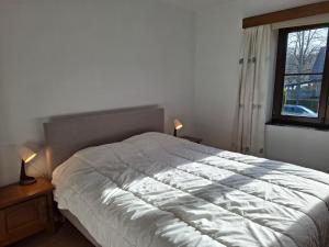 a bedroom with a white bed with two lamps and a window at L'Echappée Belle in Beauraing