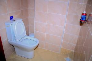 een badkamer met een wit toilet in een betegelde muur bij Luxe Homes in Meru