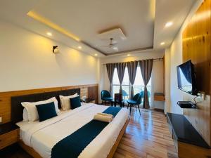 a hotel room with a large bed and a television at The Pine Mountain View A Rooftop Restaurant & Luxury Balcony Rooms! in Mussoorie