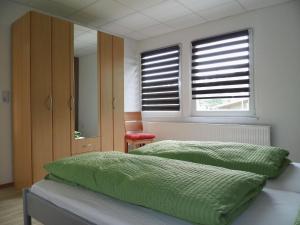 a bedroom with a bed with green sheets and windows at Apartment Fewo Berliner by Interhome in Holzdorf