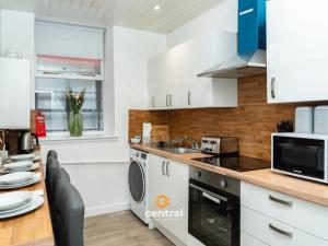 une cuisine avec des armoires blanches et un comptoir dans l'établissement The Bond by CENTRAL SERVICED APARTMENTS - 2 Bedroom - Walk Away from City Centre & Universities - Sleeps 4 - 3 x Double Beds - Smart TVs in All Rooms - Short Term Stays Welcome - Walk away from Train & Bus Station - Short Stay Favourite, à Dundee 65 autres photos