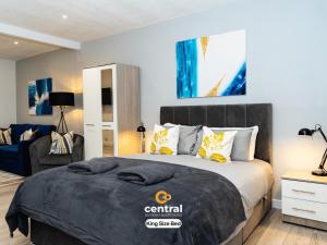 une chambre avec un grand lit et une chaise dans l'établissement The Bond by CENTRAL SERVICED APARTMENTS - 2 Bedroom - Walk Away from City Centre & Universities - Sleeps 4 - 3 x Double Beds - Smart TVs in All Rooms - Short Term Stays Welcome - Walk away from Train & Bus Station - Short Stay Favourite, à Dundee