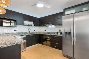 a kitchen with black cabinets and a stainless steel refrigerator at Spacious Home with Private Pool & Covered Patio Near the Beach in Playa Flamingo