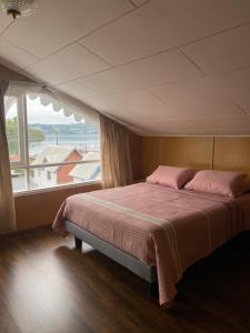 ein großes Bett in einem Zimmer mit einem großen Fenster in der Unterkunft Raíces de Gamboa in Castro