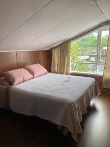 ein Schlafzimmer mit einem großen Bett mit einem großen Fenster in der Unterkunft Raíces de Gamboa in Castro