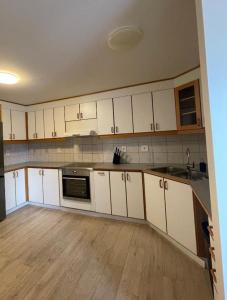 a kitchen with white cabinets and a wooden floor at IQ apartments 3 in Ytri-Njarðvík