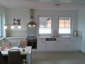 a kitchen with white cabinets and a table with chairs at Apartment 4 by Interhome in Feldhusen