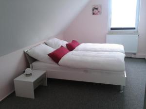 a white bed with red pillows in a bedroom at Apartment 4 by Interhome in Feldhusen +9 photos