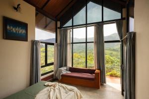 a bedroom with a bed and a large window at Kood Heritage cottages in Vagamon +14 photos